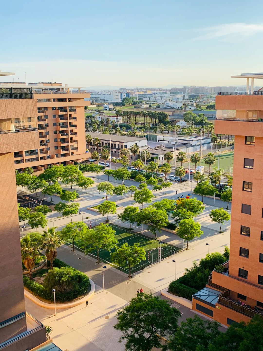 Apartment buildings surround a green park with trees and walkways.