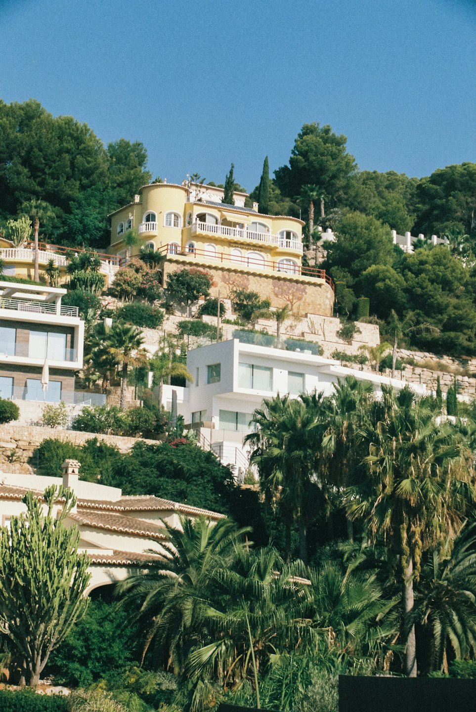 Modern villas nestle into a lush green terraced hillside.