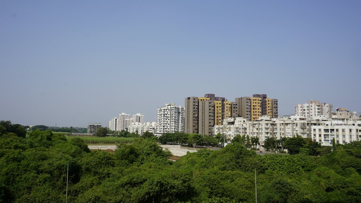 Modern and older apartment buildings stand above lush green vegetation.