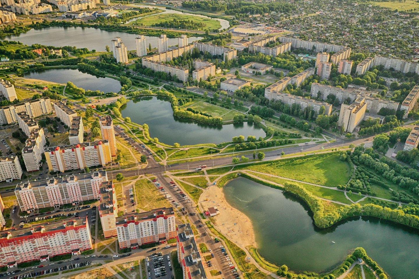 Modern apartment buildings surround interconnected lakes and green urban parks.