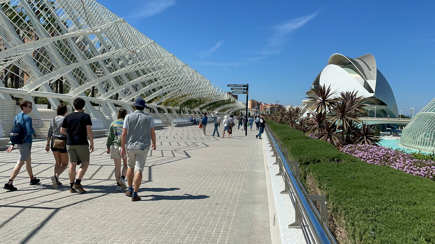 People walking along a paved path beneath a white architectural structure.